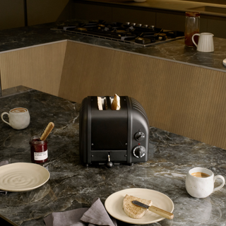 Stealth edition black toaster on a black marble kitchen countertop.