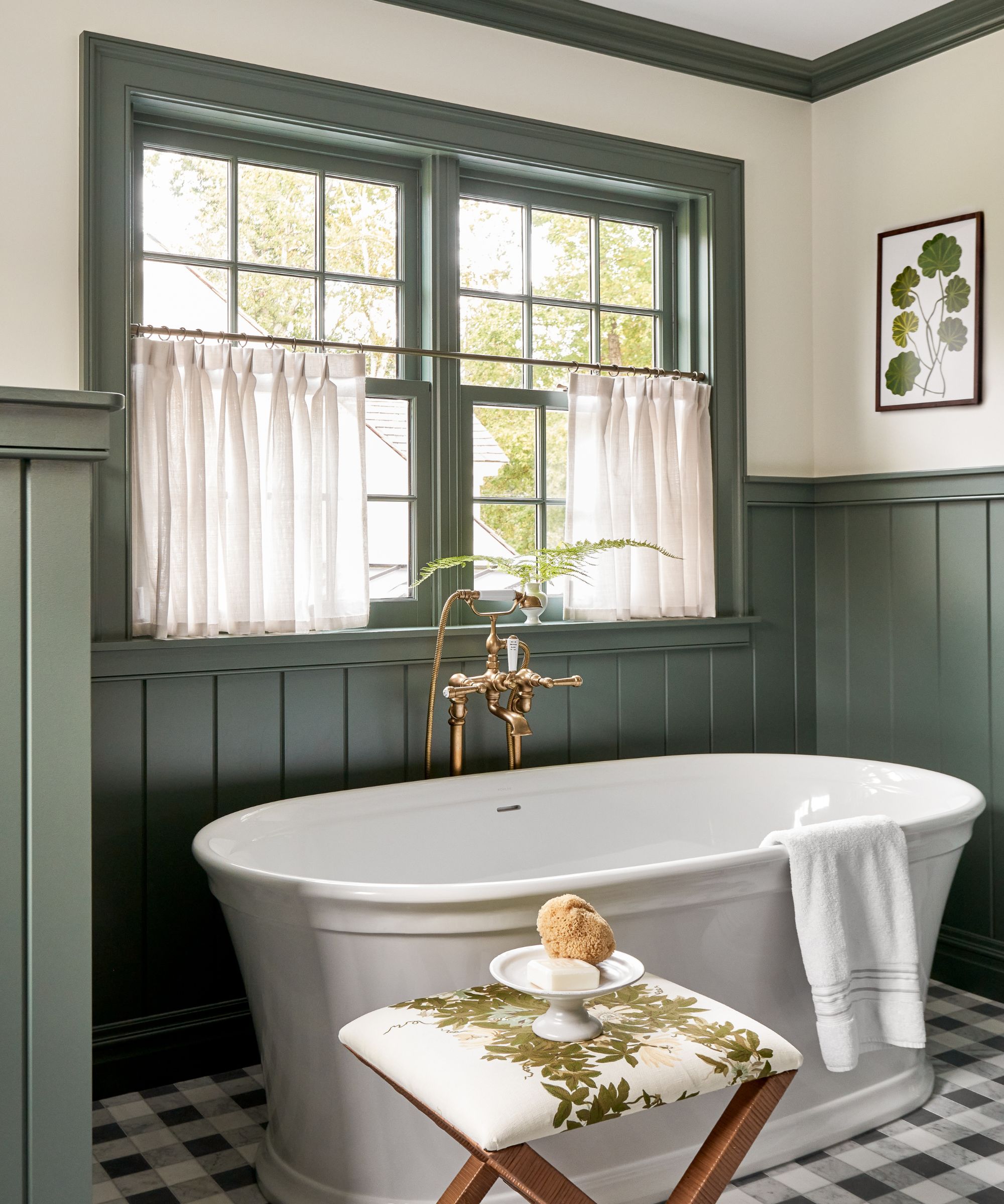 Bathroom with tiled floor, freestanding tub, stool with soap dish, green painted panelling and window frame
