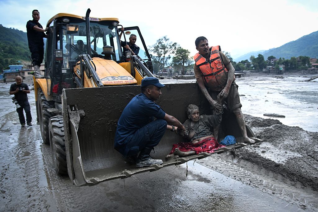 Rescuers use an excavator to transport a flood survivor, following flash floods and a landslide disaster in Devghat, in the Nepal's Nuwakot district on August 26, 2026.