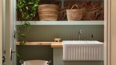 a light green laundry room with a butchers block wooden countertop