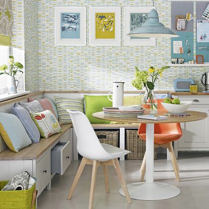 room with textured wall with round table with chairs and bench with drawers and cushions and pull-out baskets