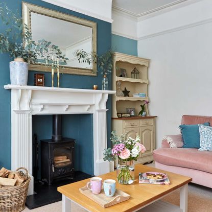 living room with log burner overmantel mirror blue and cream painted walls and pink sofa