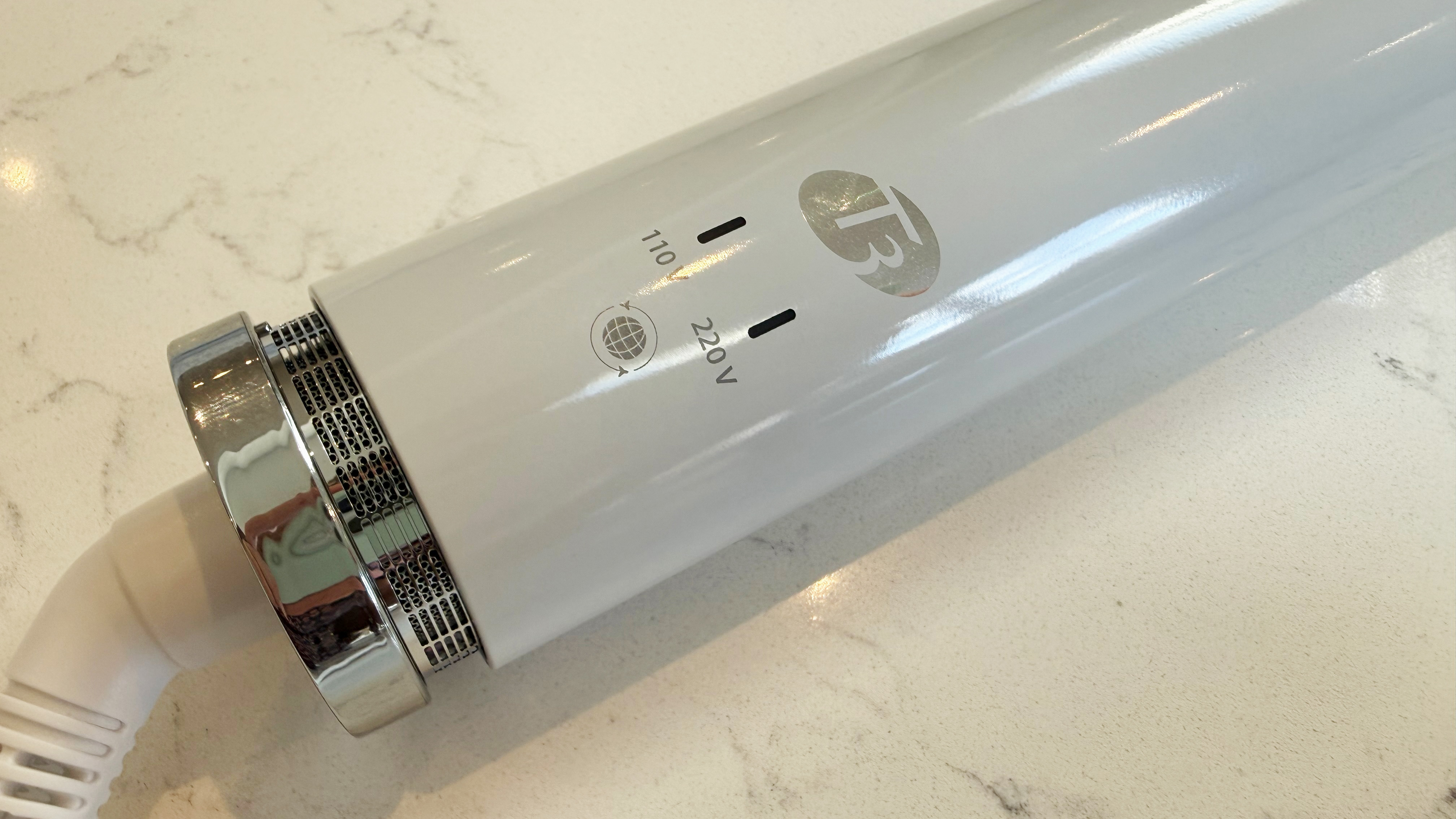 Close-up of the base of the T3 Aire 360 showing the 110V and 220V LED voltage indicators, the removable air filter and the T3 logo on a white glossy body
