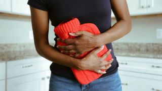 Person holding hot water bottle for bloating