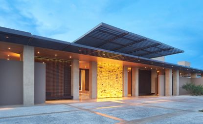 Los Cabos hotel with sand colored pillars, grey cobblestone paving and grey metal roof overhang