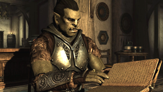 An orc stares blankly at an open book, realising his mistake, in Skyrim.