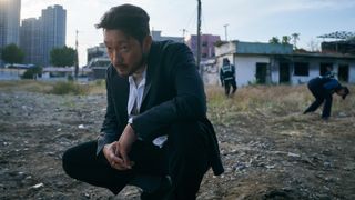 Detective Jang Nan-gam (Son Suk-ku) squatting at a crime scene in A Killer Paradox