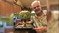 Tom Kane posing with a Yoda figurine.