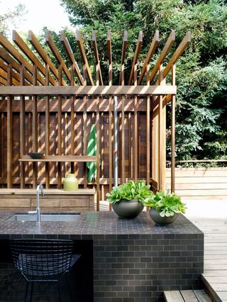 outdoor shade covering an outdoor kitchen made from black tiles