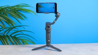 The DJI Osmo Mobile 6 tripod gimbal with an iPhone in its clamp.