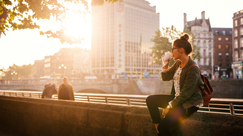 A woman sitting outside drinking her morning coffee in the sun