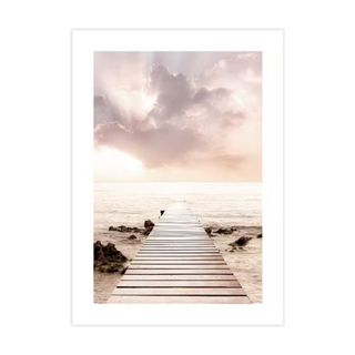 A wall art print of a sunset on the sea with a purple sky and wooden boardwalk