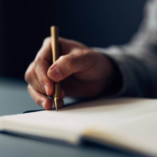 A close up of a person writing in a notebook