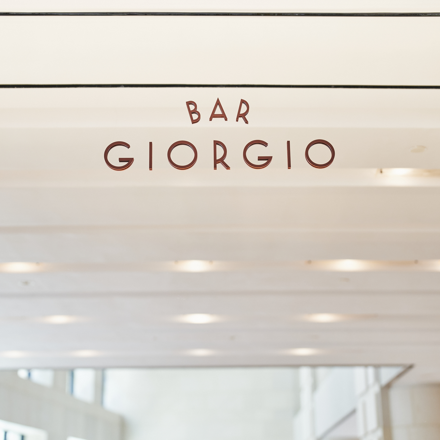 A bar's sign stands out against a mirrored wall thanks to its capped, red characters that read: BAR GIORGIO.
