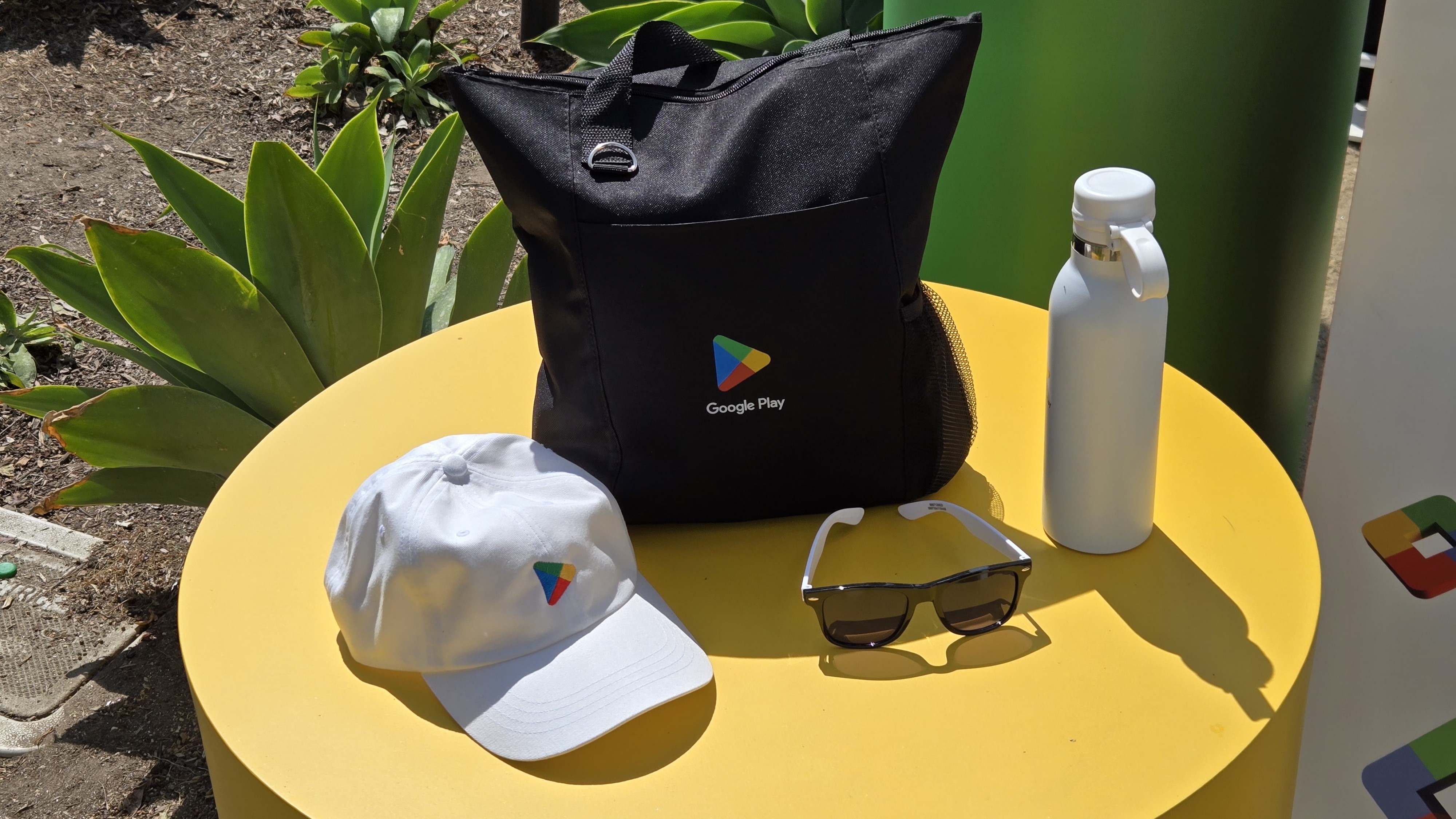 Google Play swag, including a bag, hat, sunglasses, and water bottle 