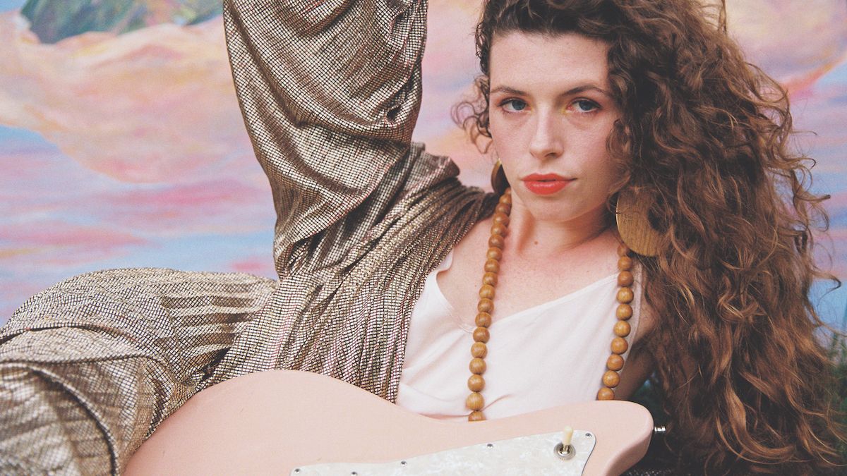 Hannah Wicklund, posing with her pink Tom Anderson Raven guitar