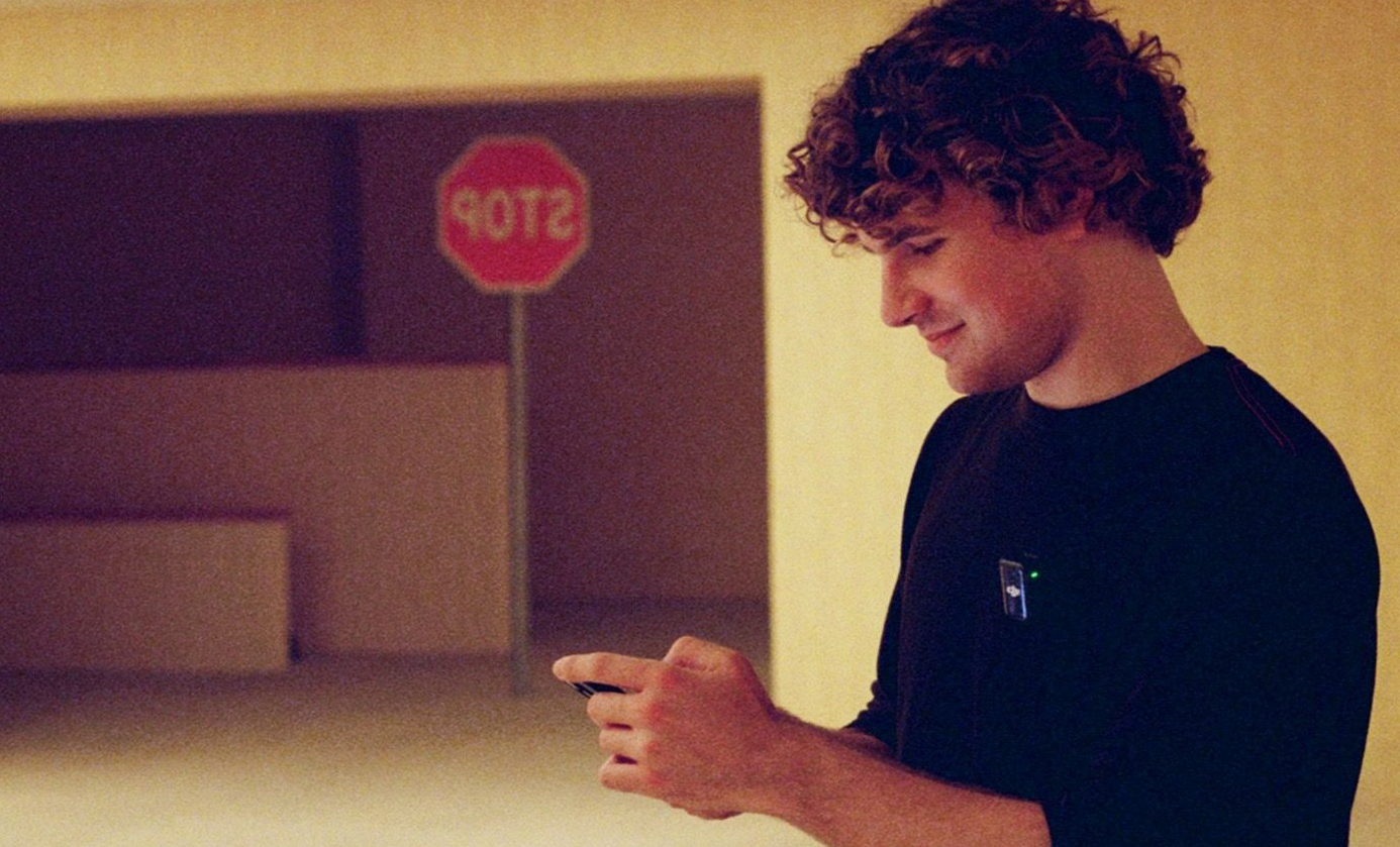 Kane Parsons on set of Backrooms, with a reversed stop sign in the background, a delicious foil for the headline which says he is not stopping making Backrooms stuff