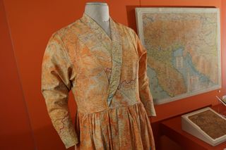 Dress made from silk escape map seen up close next to paper map, on display at museum