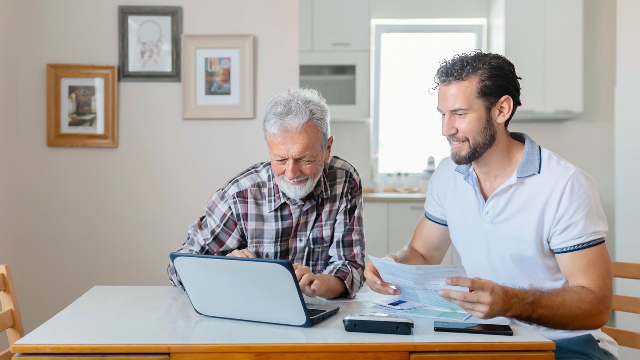 Old and young man looking at bills