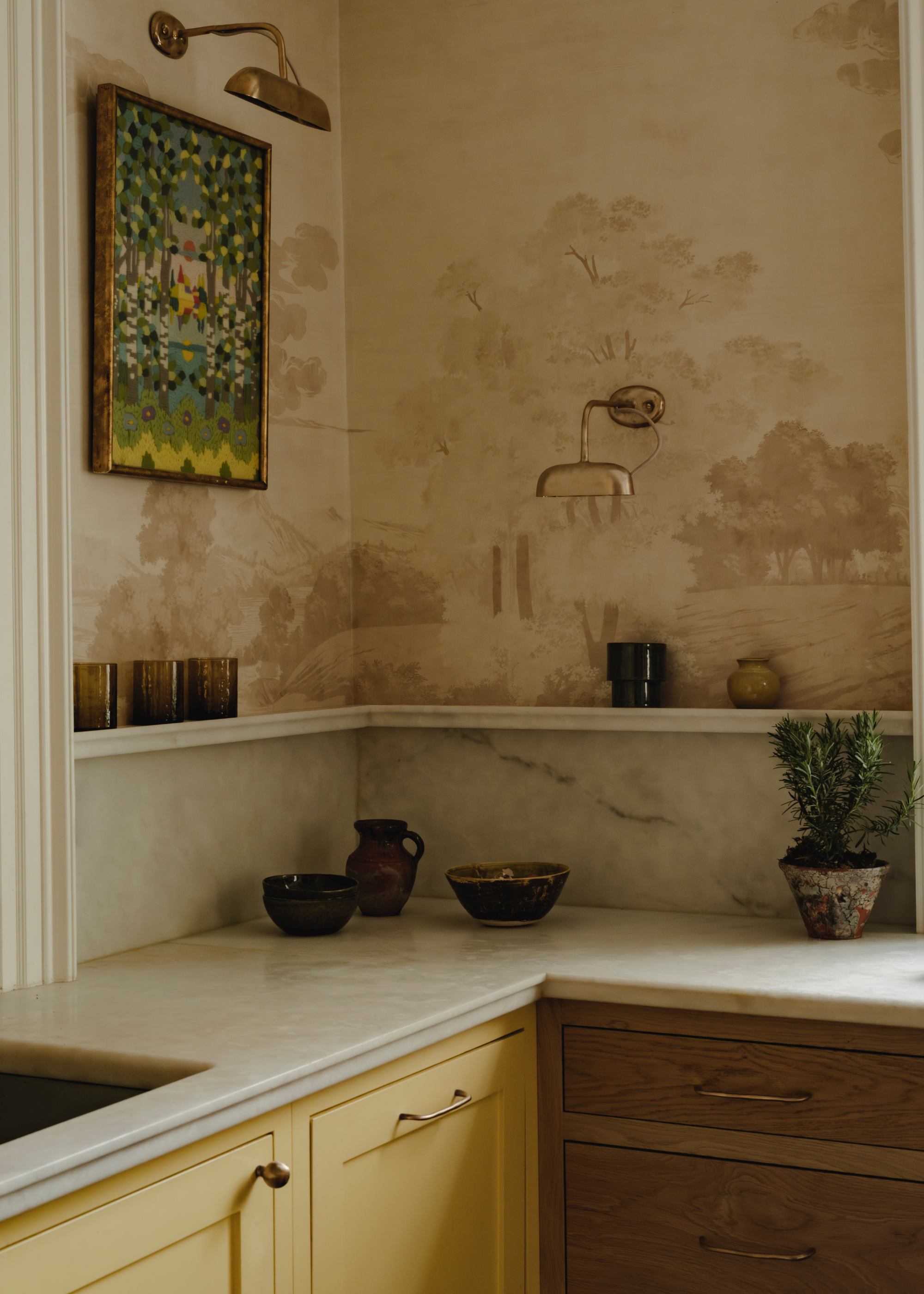 vintage inspired kitchen with wallpaper, yellow and wood cabinets, marble counters and bronze kitchen hardware