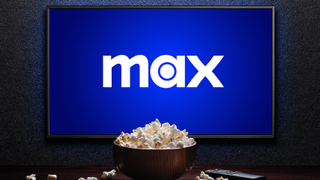 New Max logo on wall mounted TV with bowl of popcorn on table in front