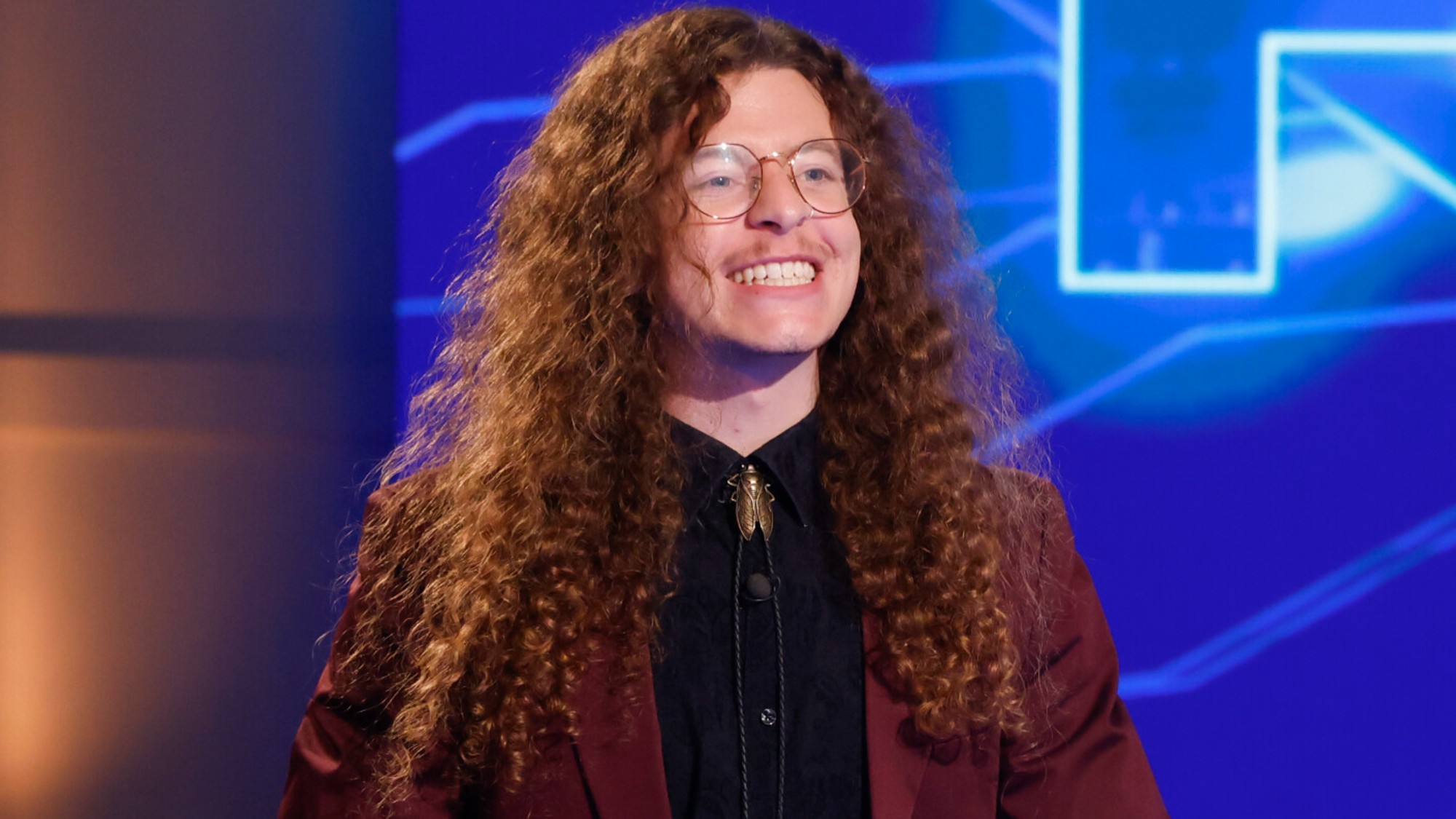 Quinn Martin in a black outfit casting his finale vote in Season 26 of Big Brother. He's smiling and there's a blue background behind him.