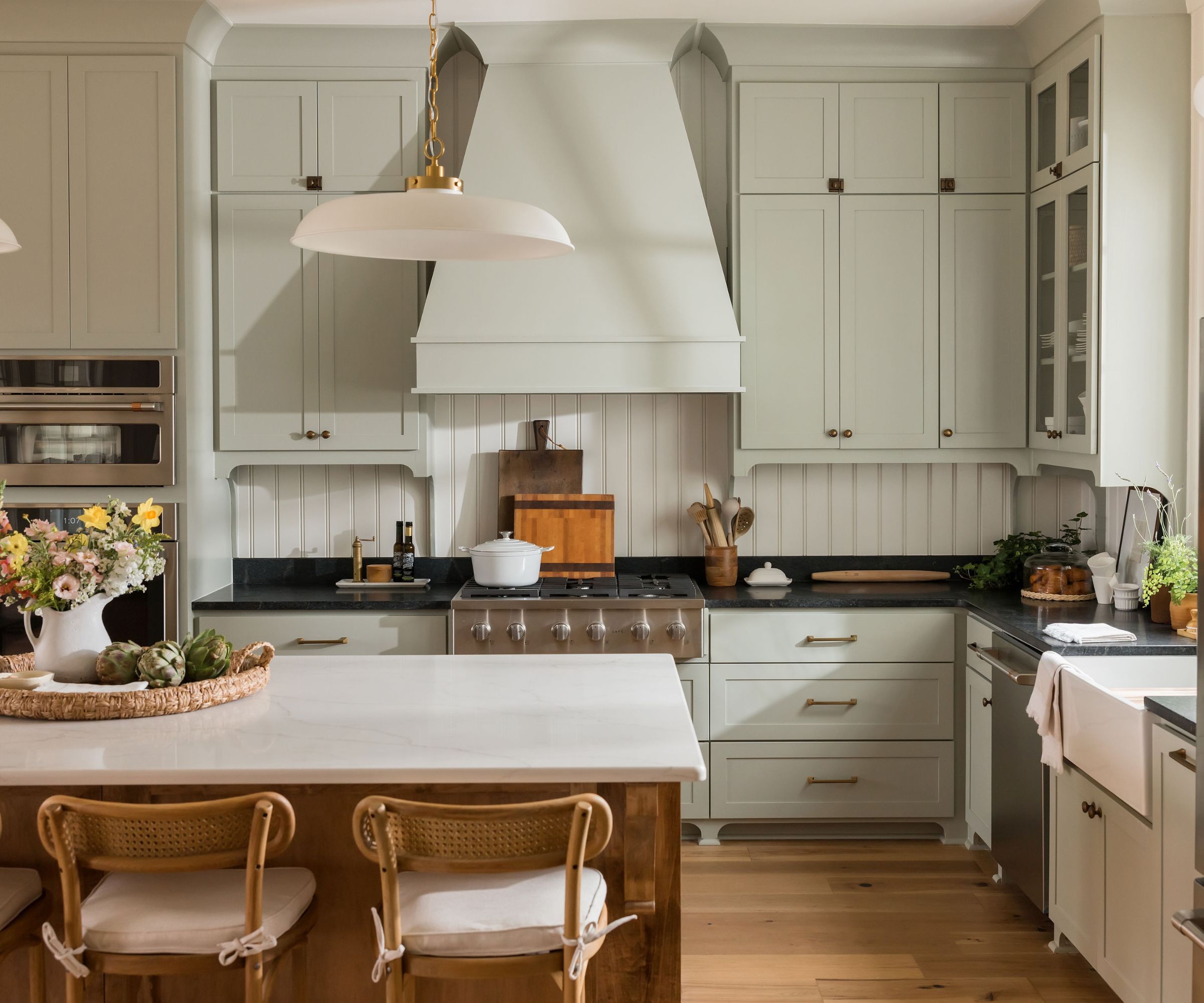 traditional kitchen with pale green cabinets, black countertops and kitchen island