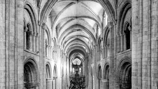 Gothic church interior featuring tall, intricately designed arches, stone walls, and ornate chandeliers in a dramatic black and white