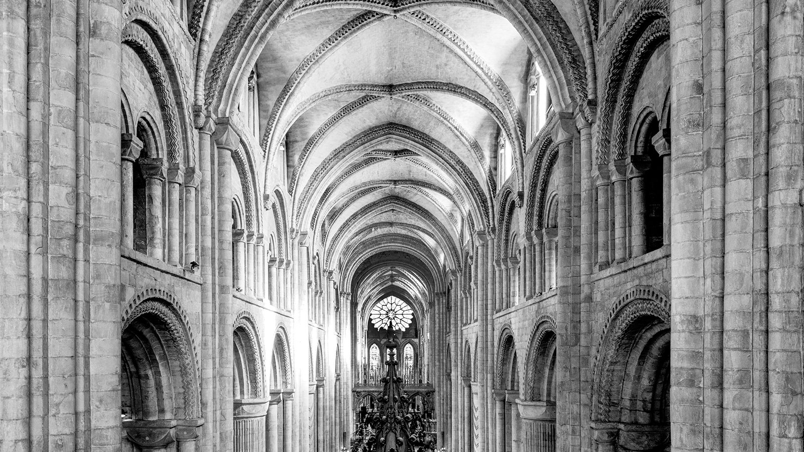 Gothic church interior featuring tall, intricately designed arches, stone walls, and ornate chandeliers in a dramatic black and white