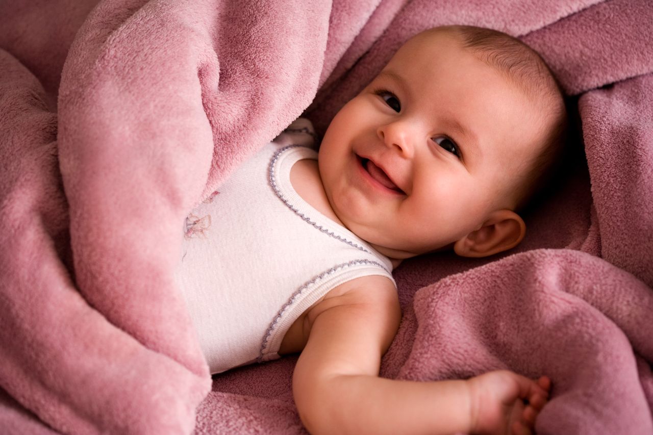 smiling baby lying on pink blanket