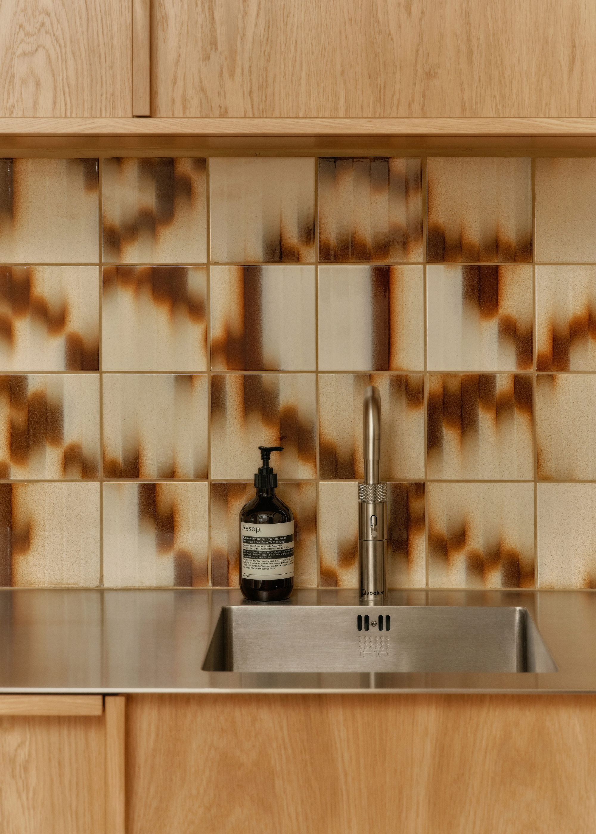 brown marble palet tiles splashback in a kitchen with wooden cabinet and steel surfaces