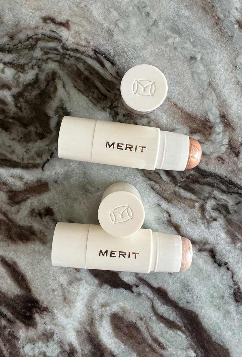 Two Merit highlighter sticks on a marble background