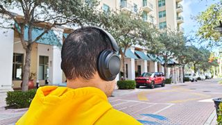 1More SonoFlow SE worn by reviewer walking down a high street testing noise-cancelling performance