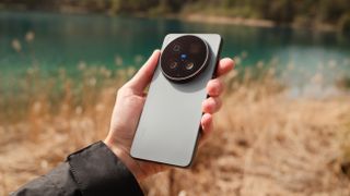 Vivo X300 Ultra held in front of a blurred lake and grass