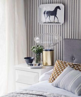 bedroom with striped paper and glass lamp