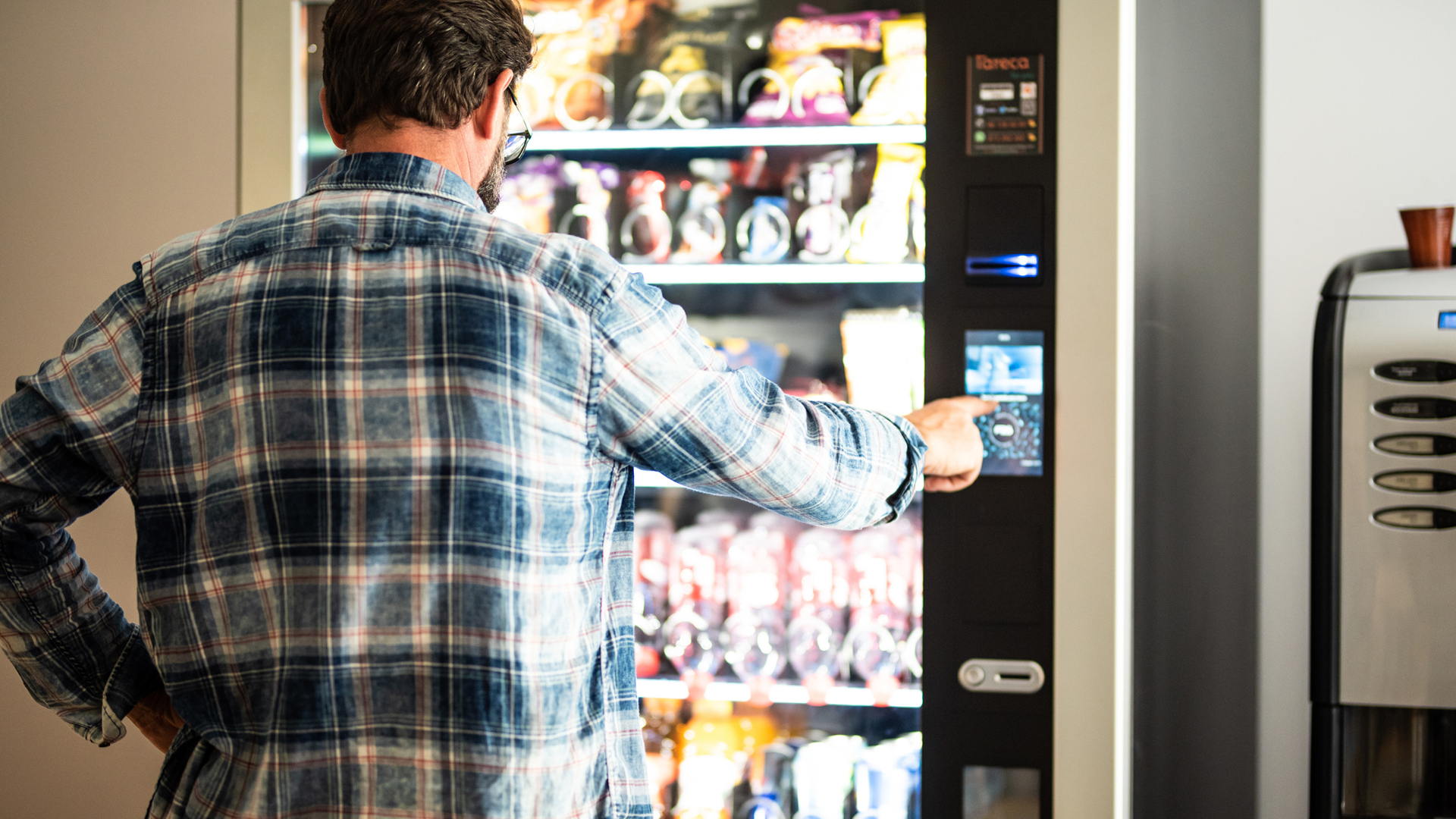 man in a checked shirt using a vending machine
