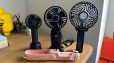 Four handheld fans on a wooden desk