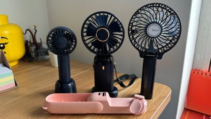 Four handheld fans on a wooden desk