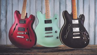 Three Squier Starcaster semi-hollow models, including the Squier Classic Vibe Starcaster, on a wooden background