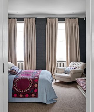 bedroom with dark gray walls, neutral curtains and colorful bed throw