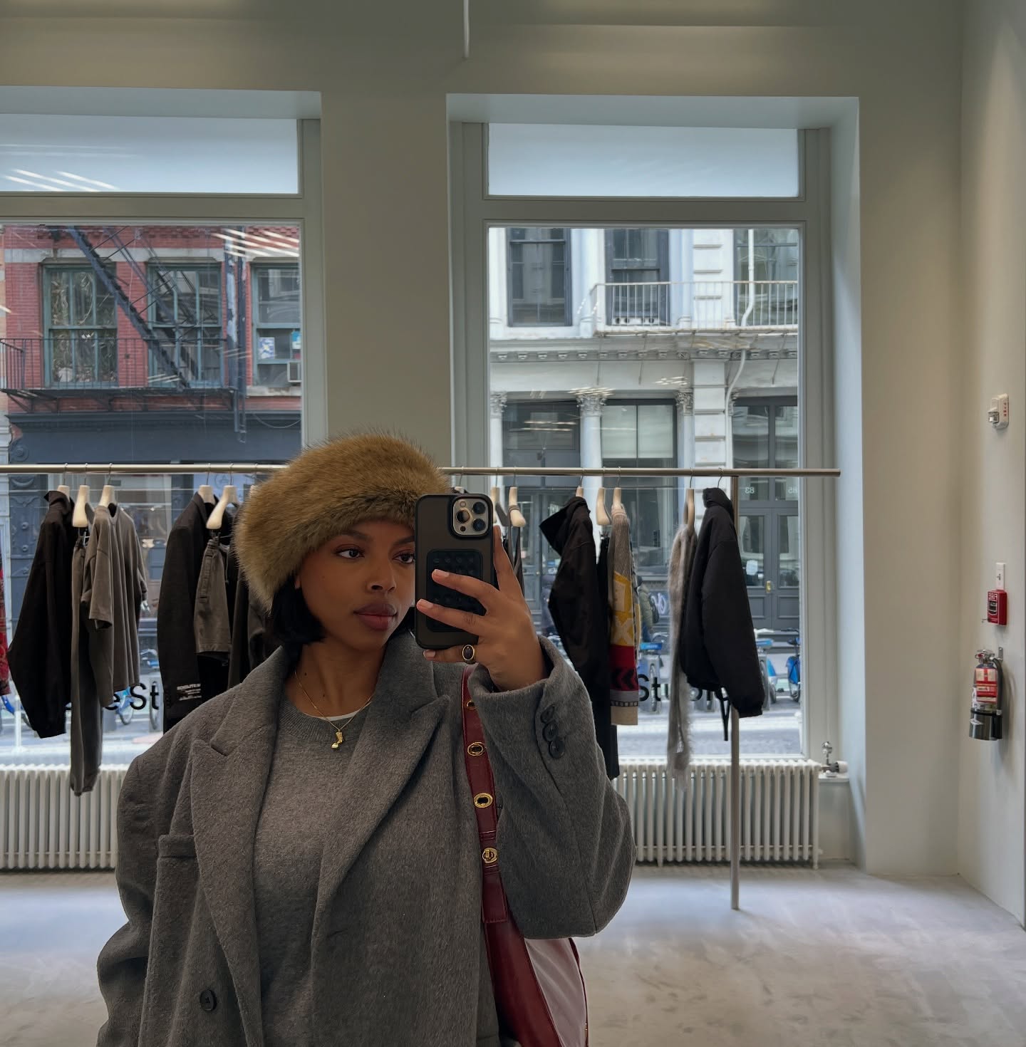 @aysha.sow in a grey crewneck sweater and blazer coat, wearing the faux-fur hat trend