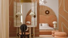 A peach and cream themed bedroom with an oversized headboard, a tiered pouf, a set of table lamps, a vanity with a wooden stool and a pair of wall sconces with a mirror