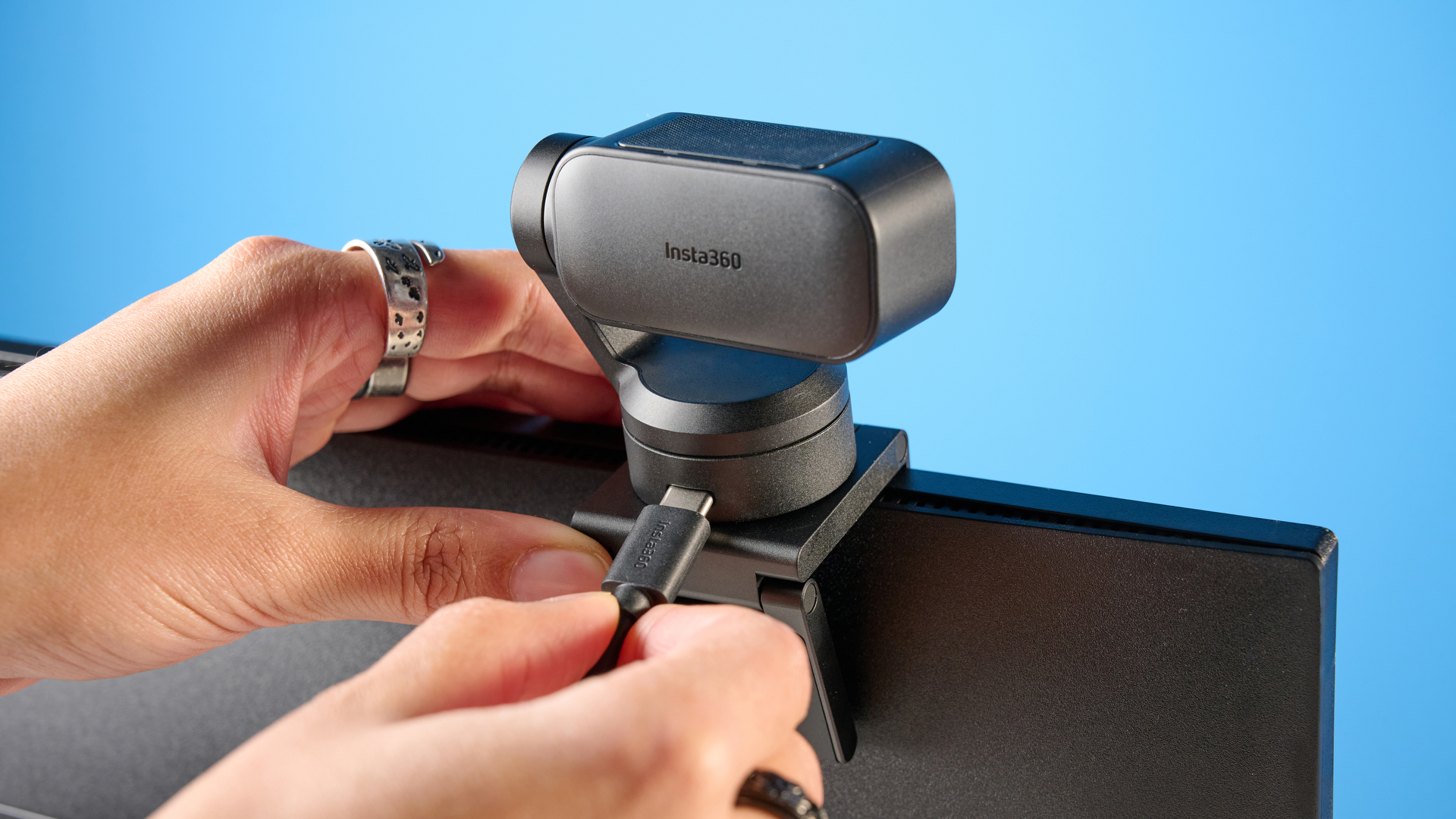 Insta360 Link 2 Pro in graphite black attached to a computer screen photographed on a blue background