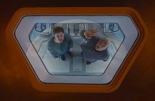 Two men look up through a spaceship's glass portal