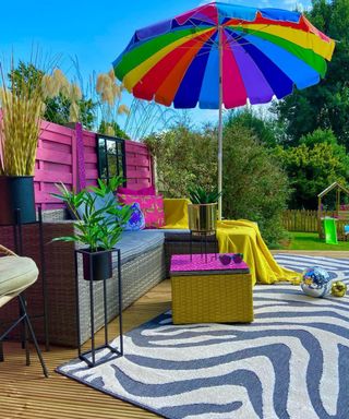 Rainbow themed deck ideas with multicolored parasol, pink painted fence,