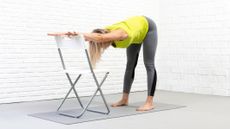 Woman performing stretch using a fold out chair to rest her hands on