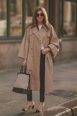 A woman wearing skinny jeans and a long trench