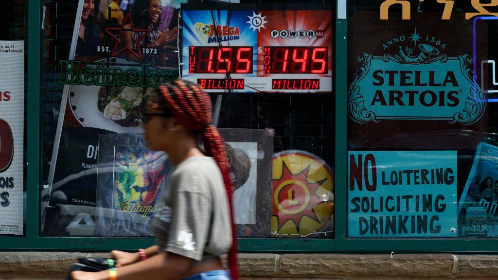 A woman walks by a liquor store advertising Mega Millions