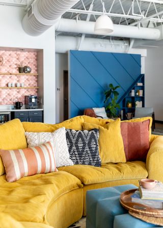 A living room with a curved yellow sofa and a blue door panel