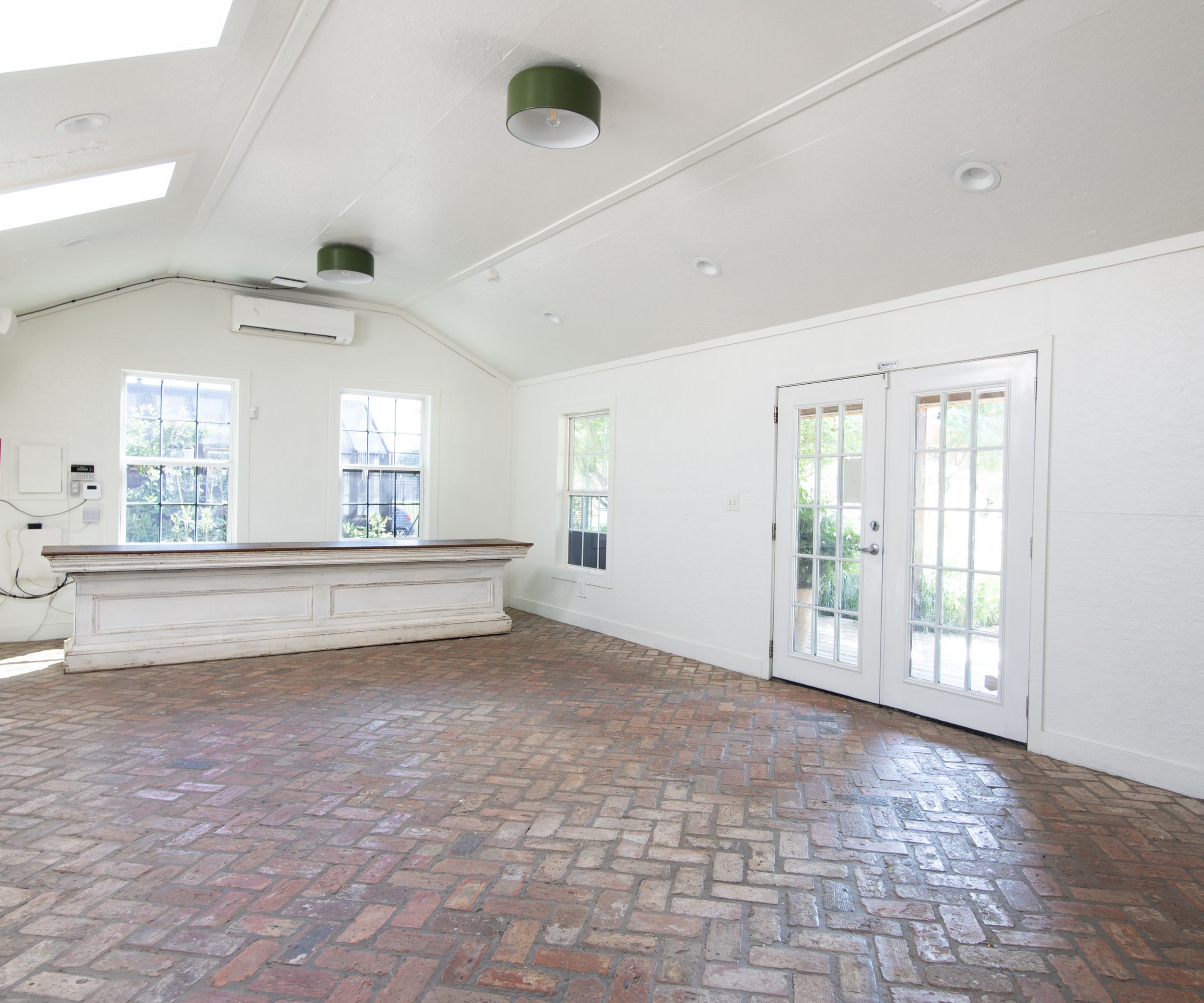 White studio with brick floor and large doors and island